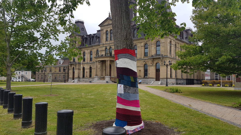 1 photo des carrés de tricot reliés pour le YARN BOMBING à POITIERS avec écrit dessus le mot surdicécité